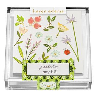 Clear acrylic Karen Adams box of gift enclosures with flowers, a ladybug and glitter. It says "Just to Say Hi" on the box