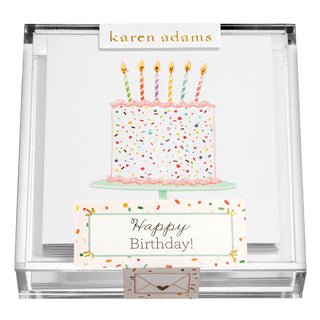Clear acrylic Karen Adams box of gift enclosures with a cake, candles and glitter. It says "Happy Birthday" on the box
