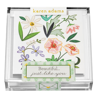 Clear acrylic Karen Adams box of gift enclosures with flowers and glitter. It says "Beautiful just like you" on the box