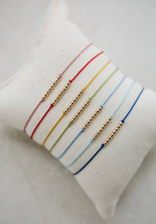 Friendship Bracelet by Abacus Row.
Each bracelet is a simple silk cord bracelet adorned with smooth 14k gold-filled beads.
 Size – adjustable, 8.0" when fully open