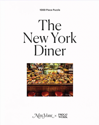 White box with black text that reads "The New York Diner" with a picture of a diner counter filled with food.