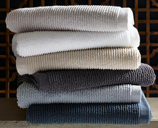 Matouk Aman bath towels stacked. Cloud, White, Nude, Anthracite, Pool and Baltic.